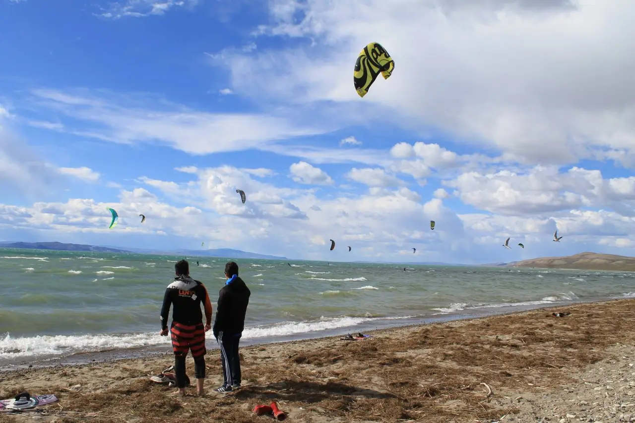 Kitesurfistas en el Lago Musters durante un encuentro de kite, con cometas en el cielo