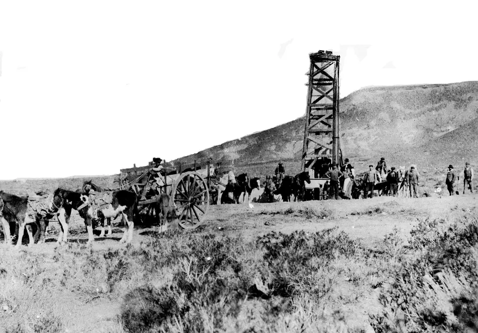 La torre del primer pozo de petróleo de Comodoro Rivadavia en 1907, con carros tirados por caballos y el cerro detrás