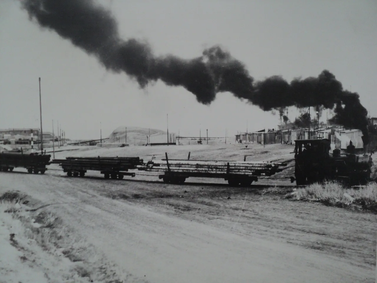 Un tren de carga de YPF cruzando el barrio Km 3, con el humo negro de la locomotora